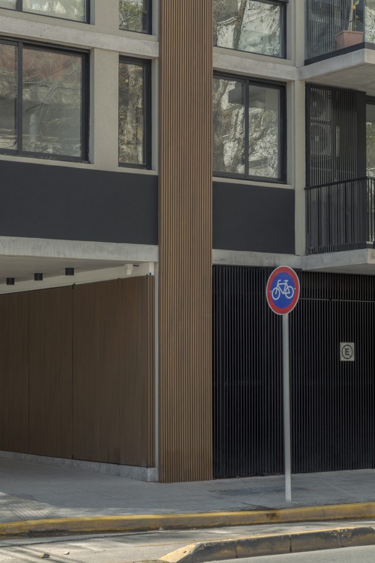 Acceso en planta baja con columna de madera y vereda